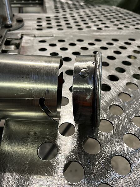 Detailní pohled na víčko a systém jeho zavěšení na trubici.